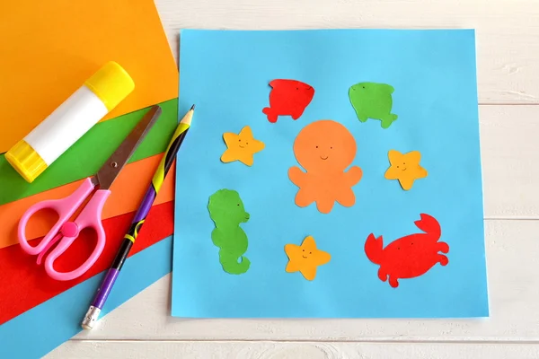 Papieren zeedieren op een blauwe kaart. Lijmstok, schaar, potlood, gekleurd papier. Kleuterschool en kleuterschool papier ambachten. Doe-het-zelf project. Kleuterschool — Stockfoto