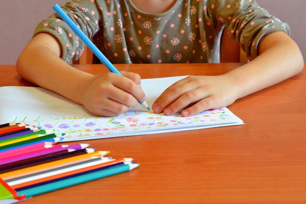 L'enfant s'assoit et dessine des fleurs. L'enfant tient un crayon dans sa main. Un ensemble de crayons de couleur sur une table. Dessin d'enfants. Enfants dessinant des idées jardins d'enfants projets artistiques pour les enfants. Dessiner des activités pour les enfants d "âge préscolaire. Apprentissage du dessin pour les enfants — Photo