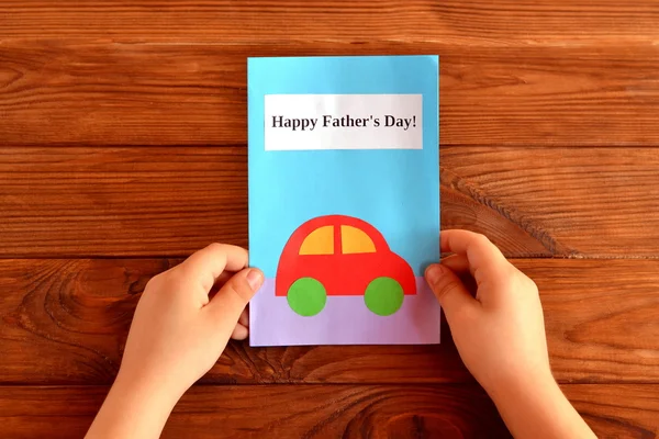 Gratulationskort fars dag. Barnet innehar ett hälsningskort i handen. Lycklig fars dag. Lätt barn hantverk — Stockfoto