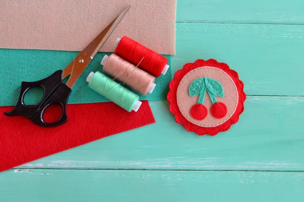 Cute felt brooch with red cherries and green leaves. Beautiful summer accessory for girls and women. Home made decoration brooch. Felt sheets thread kit, scissors, needle. Crafts supplies and tool — Stock Photo, Image