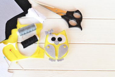 Baykuş oyuncağı hissettim. Doldurulmuş baykuş desenli dikiş. Keçeli kalem, makas, iplik, iğne, iğne, dikiş seti. Metin için kopyalama alanı olan tahta arkaplan