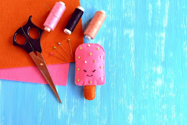 Handmade felt ice cream pattern. Cute toy on blue wooden background with empty place for text. Easy craft idea for kids. Scissors, thread, needle, pins, felt set. — Stock Photo, Image