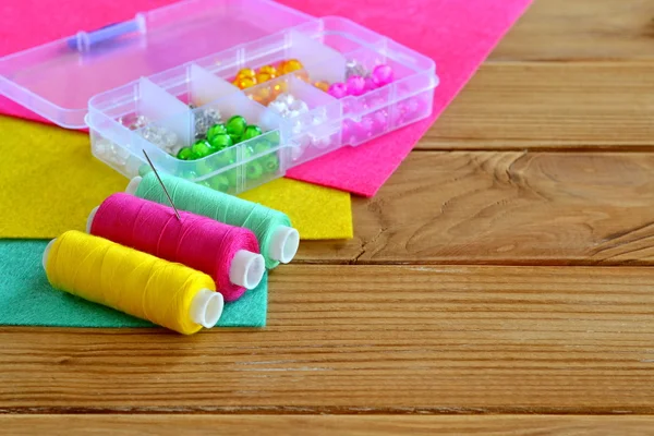 Organizador con varias cuentas, hilo de colores, aguja, piezas de fieltro. Fondo de madera con espacio vacío para texto. Kit de costura fondo. Objetos de costura — Foto de Stock