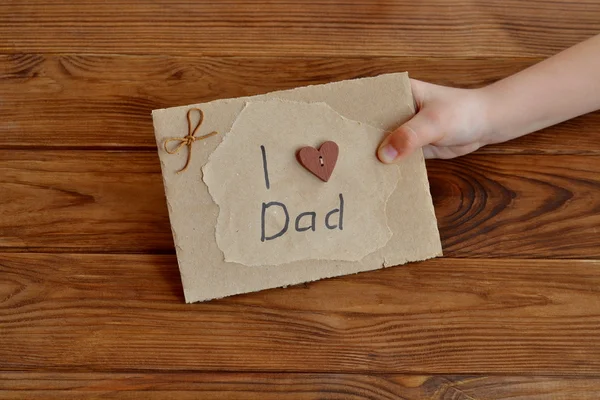 Маленький ребенок держит карту, которую я люблю папу. Открытка из картона и оберточной бумаги, украшенная деревянным сердцем, восковым шнуром. День отца или поздравительную открытку. Идея подарка для папы от дочери — стоковое фото