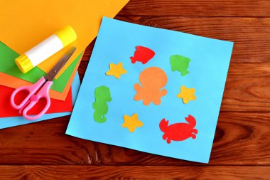 Paper applique with sea animals and fishes. Art lesson in kindergarten. Paper sea animals - octopus, fish, starfish, seahorse, crab. Kids diy. Sheets of colored paper, scissors, glue clipart