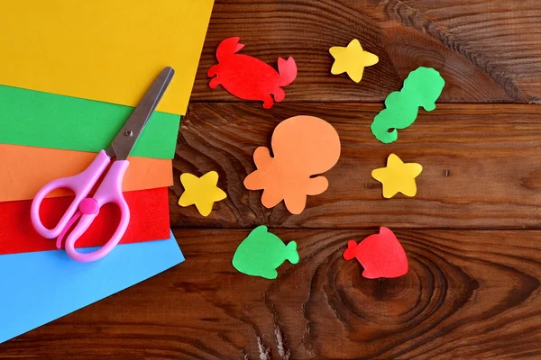 Papier-zeedieren - octopus met vis, zeester, seahorse, krab. Kinder papier ambachten. Kinderen diy. Vellen gekleurd papier, schaar op houten achtergrond — Stockfoto