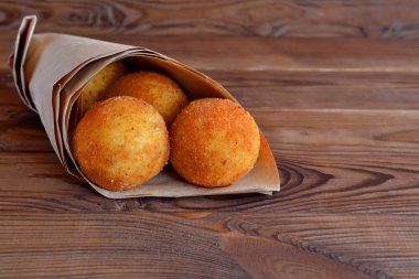 Arancini topları. Kızarmış pirinç topları kağıt kahverengi ahşap zemin üzerinde. Aperatif, Sicilya sokak gıda