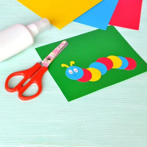 Детские картонные изделия - цветная гусеница на зеленом листе бумаги. Ножницы, клей, бумажные простыни. Набор для детского искусства — стоковое фото