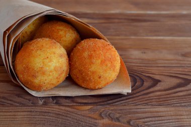Arancini pirinç topları. Kızarmış pirinç topları kağıt kahverengi ahşap zemin üzerinde. Aperatif, sokak gıda