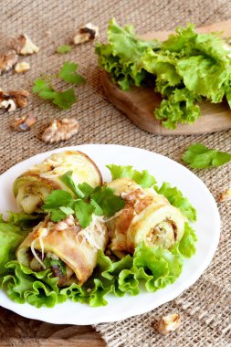 Kızarmış kabak peynir, ceviz ve otlar ile doldurulmuş. Bir ahşap tahta üzerinde taze yeşil salata. Sağlıklı ve lezzetli yaz gıda
