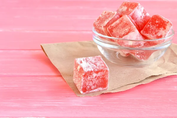 Delicious turkish delight in bowl on pink wooden background, one turkish delight on brown paper — Stock Photo, Image