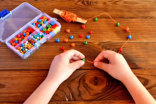 Mani di bambini che tengono perline e cordone. Bambino gioco sensoriale — Foto Stock