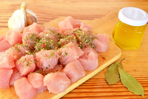 Tumpukan potongan daging sapi mentah di papan potong kayu, bawang putih, rempah-rempah, minyak zaitun, daun kering — Stok Foto