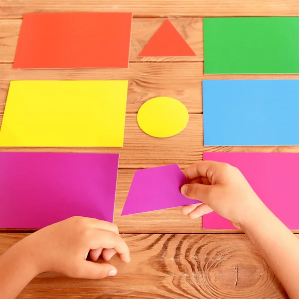 Niño pone la figura de cartón en la tarjeta de color correspondiente. Conjunto de tarjetas de entrenamiento para niños en una mesa de madera. Cómo enseñar colores para niños. Desarrollo del bebé — Foto de Stock