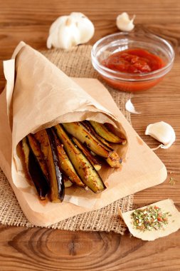 Çıtır çıtır kızarmış patlıcan sarımsak, baharatlar ve domates sos ile dilim. Domates sosu cam kase, baharat, sarımsak ahşap arka plan üzerinde