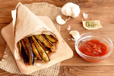 Kızarmış patlıcan kağıt ve bir kesme tahtası üzerinde şeritler. Sarımsak, baharatlar, ahşap masa üzerinde cam tabak içinde ketçap