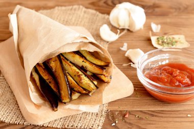 Çıtır çıtır kızarmış patlıcan dilimleri sarımsak ve baharat ile. Domates sosu cam kase, baharat, sarımsak ahşap arka plan üzerinde