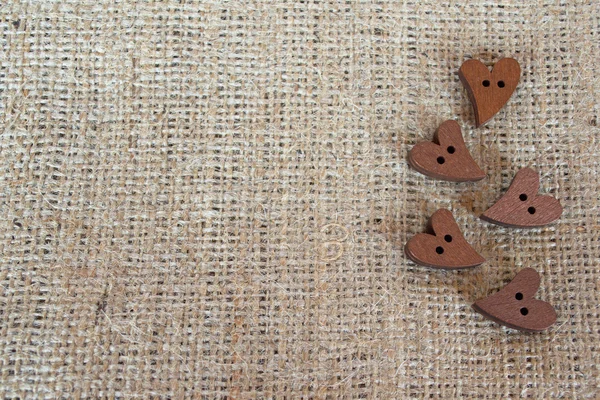 Botones de madera corazones en la arpillera. Fondo de San Valentín con espacio de copia vacío para texto — Foto de Stock