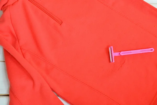 La cuchilla de afeitar, el jersey rojo infantil - como limpiar la ropa. Afeitarse y quitar las pastillas, bobbles, pelusa o pelusa de un suéter. Fácil hacks baratos para traer suéteres de nuevo a la vida. Manera de presupuesto simple para renovar ropa vieja — Foto de Stock