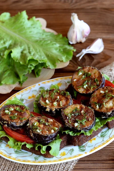 Pane tostato scuro con melanzane fritte, pomodori freschi, lattuga, aglio, aneto. Lattuga verde sulla lavagna, aglio. Panini sani con verdure su piatto su sfondo di legno — Foto Stock