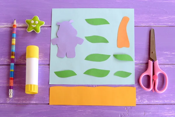 Hippopotame, feuilles, tronc de palmier coupé à partir de papier coloré. Set pour des projets artisanaux pour enfants. Carte papier hippopotame artisanat. Bâton de colle, ciseaux, crayon, gomme sur fond bois. Vue du dessus — Photo