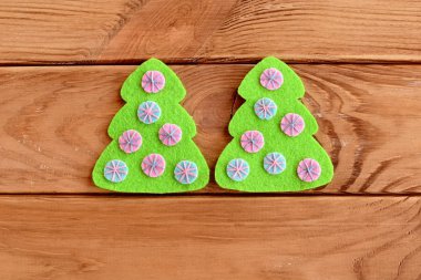 Ahşap arka planda pembe ve mavi topları olan yeşil keçeli ağaç. Noel ağacı dikilmiş gibiydi. Albüm süslemesi. El sanatları özel dersi. Dikiş dersi. Adım at. Üst Manzara. - Yakın çekim. Tutumlu Noel fikirleri hediyeleri yok eder.