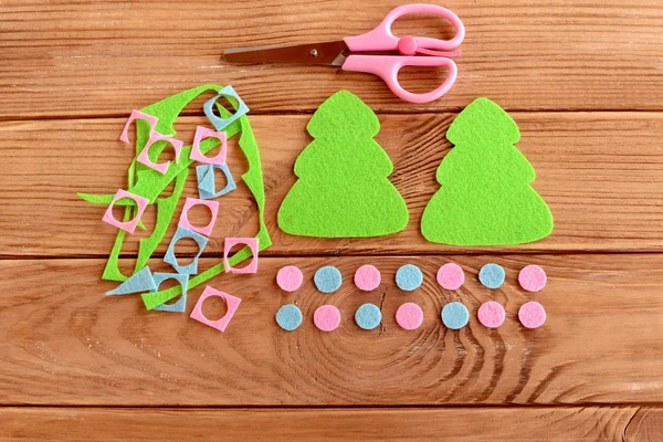 Two green felt Christmas trees, pink and blue balls set, scissors, felt scraps on a wooden table. Home Christmas tree decor crafts idea. Step. Top view. DIY frugal Christmas decor for kids — Stock Photo, Image