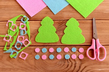 Felt Christmas tree decoration patterns. Felt scraps, scissors on wooden background. Christmas New year tree toy crafts background. DIY needlework tutorial step by step. Winter art project for children. Making Christmas decorations