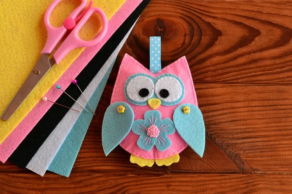 Cute pink and blue owl toy, colored felt sheets, scissors on a wooden table. Fabric owl embellishment. Hand pretty felt ornament. Children crafts project — Stock Photo, Image