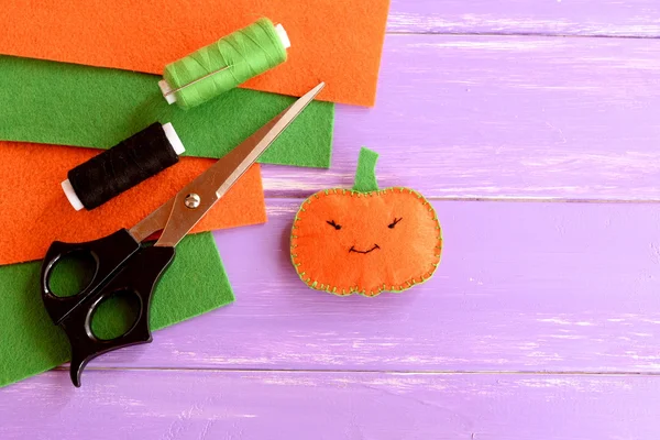 Cute felt pumpkin decor, threads, scissors, needle, felt sheets on lilac wooden background with copy space for text. Halloween sewing crafts for kids. Easy project for Halloween pumpkin — Stock Photo, Image
