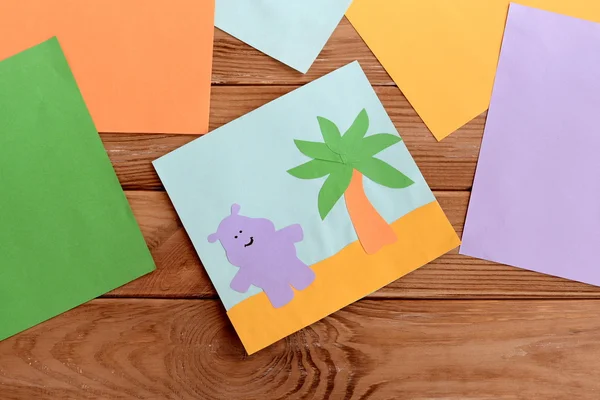 Carta di carta con ippopotamo felice e una palma, fogli di carta colorati su un tavolo di legno. Scuola materna arte e attività artigianale per i bambini. Divertente sfondo bambini — Foto Stock