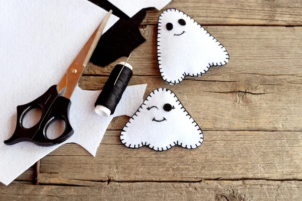 Cute little white ghosts crafts, felt sheets, scissors, thread, needles on an old wooden background. Easy Halloween felt pattern ghosts. Halloween sewing project for children — Stock Photo, Image