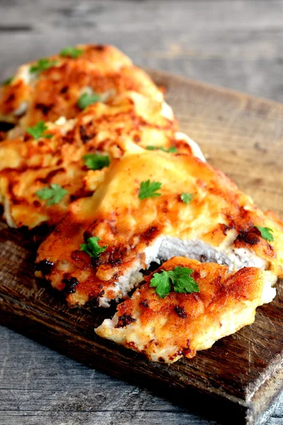 Steaks de dinde frits dans la pâte servie avec du persil vert. Délicieuse viande de dinde sur panneau de cuisine en bois. Recette de côtelettes facile et délicieuse. Gros plan — Photo