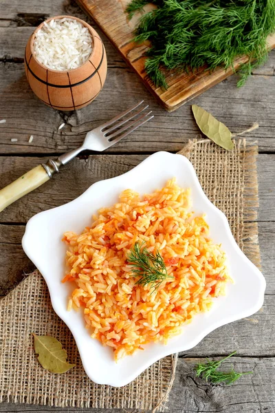 Risotto mit Gemüse auf dem Teller. Reis mit Karotten, Tomaten, Knoblauch und Gewürzen gekocht. Vegetarier und Ernährungsrezept. Ansicht von oben — Stockfoto