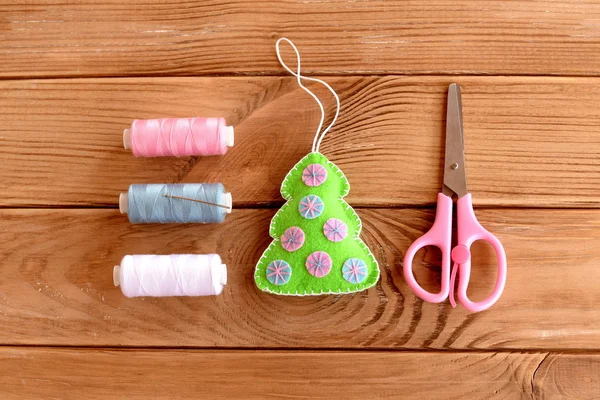 Felt Christmas tree ornament, thread, scissors, needle on a wooden background. Christmas season craft idea for kids. Step. Top view — Stock Photo, Image