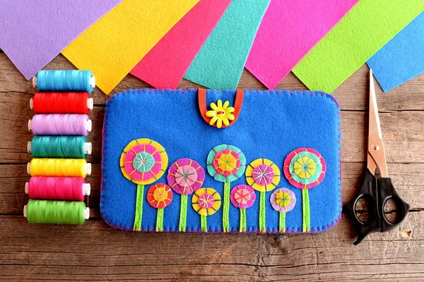 Tablet için kılıf. Parlak çiçekler, iplik kiti, keçe levhalar, eski ahşap arka plan üzerinde makas ile keçe mavi durumda. Tablet bilgisayar için Diy dikiş. Üst te. Closeup 