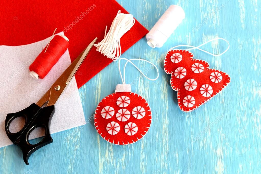 Red felt Christmas tree decor, scissors, red and white felt sheets, thread,  needle on wooden background with empty space for text. Home sewing crafts.  Beautiful and quick decoration idea for Christmas Stock