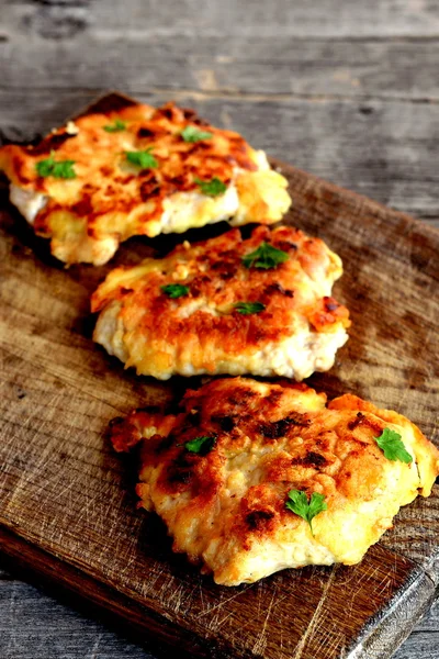 Dada goreng Turki di adonan pada papan kayu. Potongan kalkun digoreng dalam minyak sayur di atas panci dan ditaburi dengan peterseli segar — Stok Foto