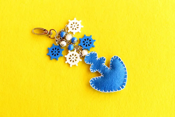 Portachiavi di ancoraggio in feltro decorato con perline e piccola ruota decorativa. Bellissimo portachiavi per auto o borsa da spiaggia isolato su sfondo feltro giallo. Charm accessorio. Estate fai da te idea — Foto Stock