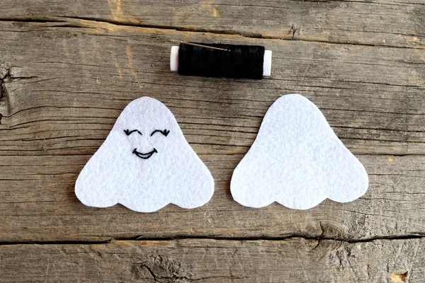 Cut from white felt details to create Halloween ghost. On one side embroidered with black thread eyes and mouth. Step. The sewing tutorial for children. Old wooden background. DIY Halloween ghosts decorations — Stock Photo, Image