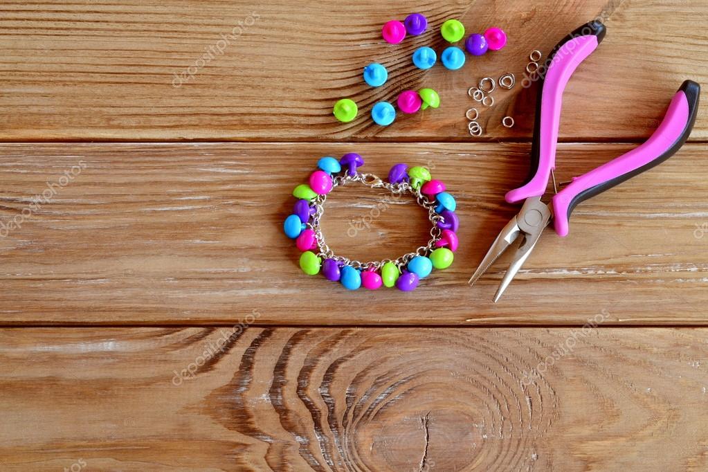 Button bracelet. Set of bright colored buttons, pliers. DIY bangle jewelry  idea. Easy make creative crafts. Bracelet made out easily available  materials. Wooden background with space for text Stock Photo by ©OnlyZoia