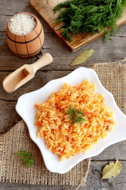 Bir tabak, dereotu dal, kesme tahtası, eski ahşap zemin üzerine kaşık sebze risotto. Basit vejetaryen pilav tabağı