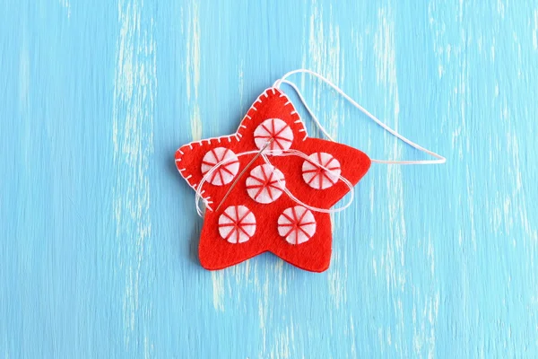 Join the felt edges of Christmas star decorations hanging with white thread using a decorative blanket stitch. Two felt details of Christmas star diy on a blue background. Winter crafts instruction for kids step. December decorations diy. Closeup — Stock Photo, Image