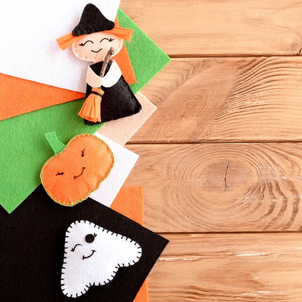 Красивый Хэллоуин украшения игрушки и войлочные простыни на деревянном фоне с пустым местом для текста. Маленькая ведьма, тыквенная голова и призрак из войлока. Детские поделки. Хэллоуин — стоковое фото