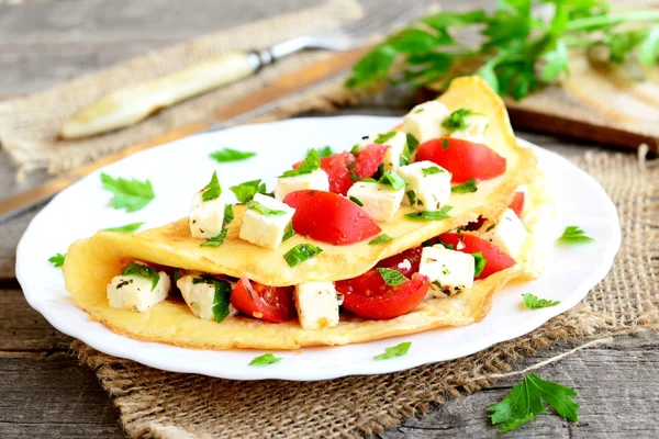 Leher dadar yang lezat di papan kayu. Omelet telur goreng dengan isian tomat ceri, keju dan peterseli. Mudah memasak sarapan. Garpu, pisau, parsley sprigs pada latar belakang kayu. Penutup — Stok Foto