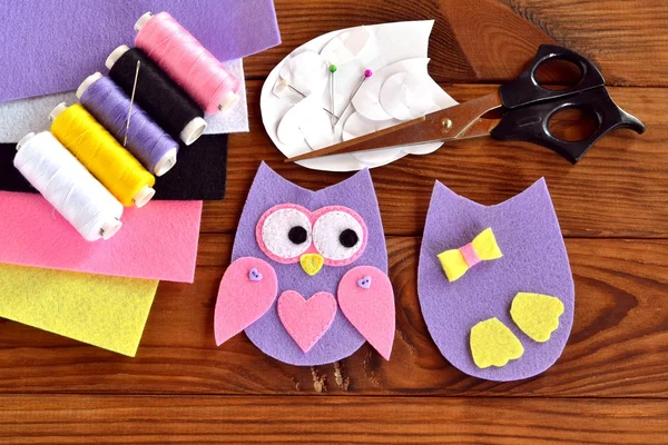 Set for sewing a felt owl, paper templates, felt sheets, scissors, thread, needle, pins on a brown wooden background — Stock Photo, Image