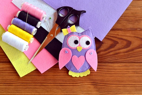 Handmade felt owl, felt sheets, scissors, thread, needle, pins on a brown wooden background — Stock Photo, Image
