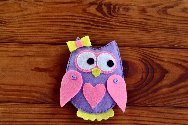 Cute handmade felt owl with bow and heart isolated on a brown wooden background — Stock Photo, Image