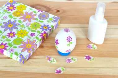 Dekupaj Paskalya yumurtası, tutkal, doğal ahşap arka plan üzerinde çiçek desenli peçeteler. El yapımı kağıt zanaat. Çiçek motifleri ile süslenmiş Paskalya yumurtası