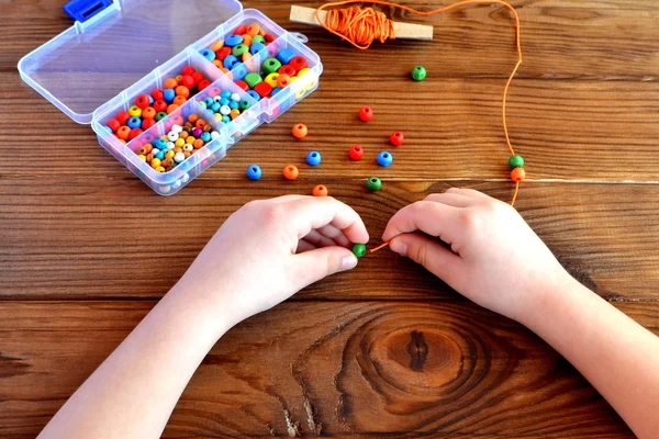 Mani di bambini che tengono perline e cordone. Bambino gioco sensoriale — Foto Stock